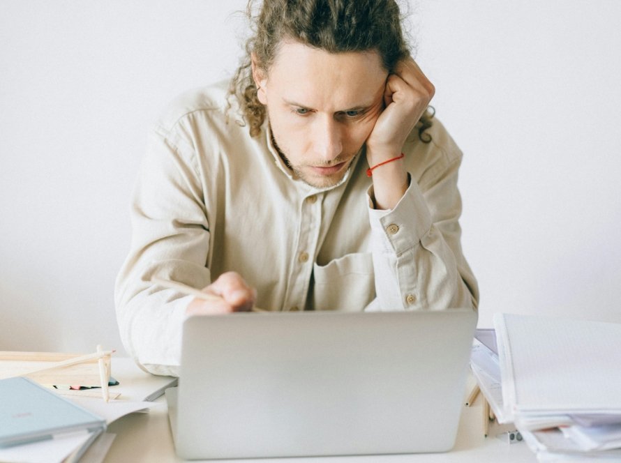 Adult man stressed at work, experiencing burnout while working on laptop at desk.