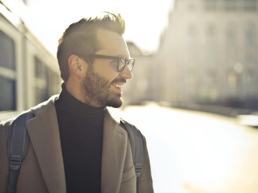 Smiling man with glasses and coat enjoying a sunny day in Budapest.