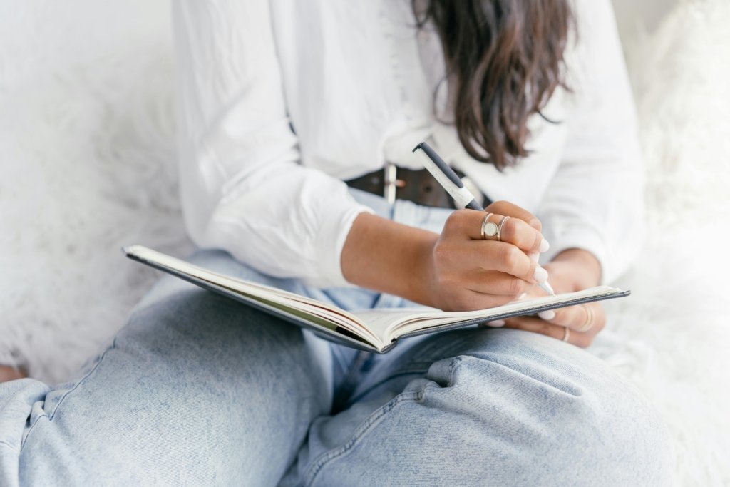 Close-up of a woman writing in a notebook, showcasing creativity and focus.